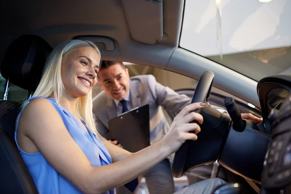 Happy woman with car dealer in auto show or salon