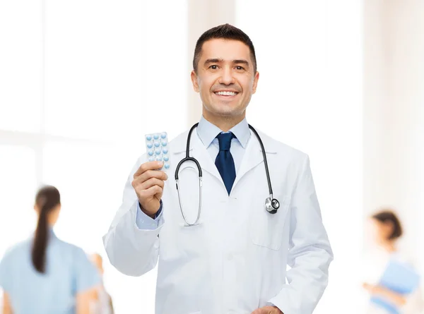Smiling male doctor in white coat with tablets