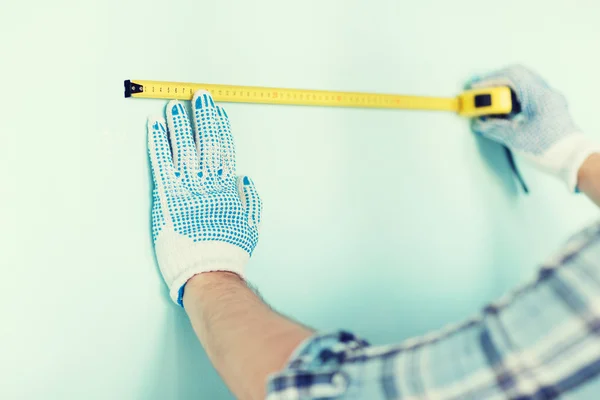 Closeup of male in gloves measuring wall with tape