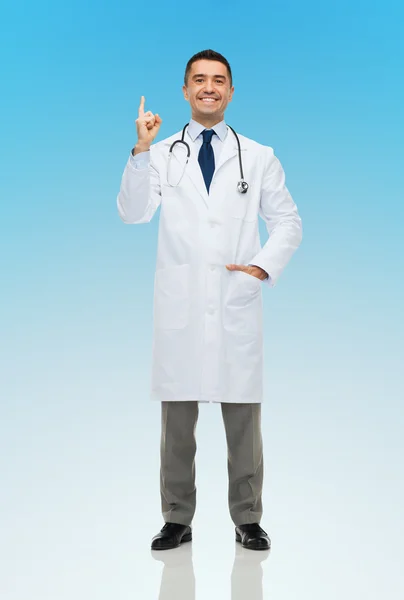 Happy male doctor in white coat pointing finger up