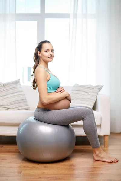 Happy pregnant woman exercising on fitball at home