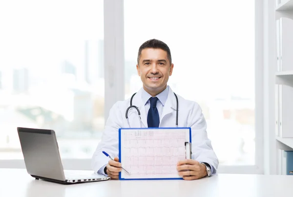 Happy doctor with clipboard and laptop in office
