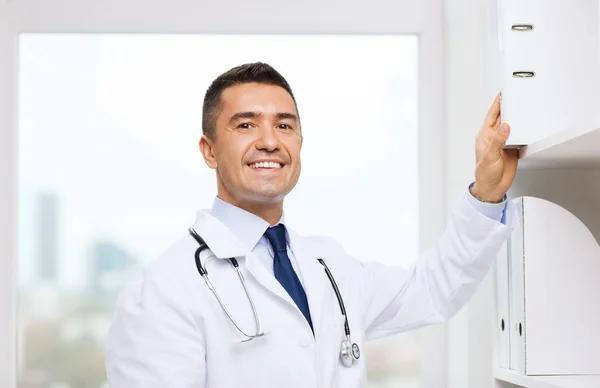 Happy doctor with clipboard in medical office
