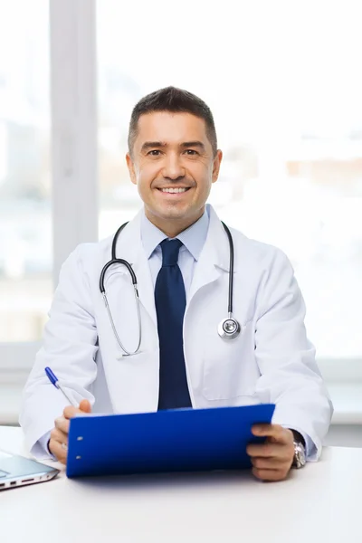 Happy doctor with clipboard in office