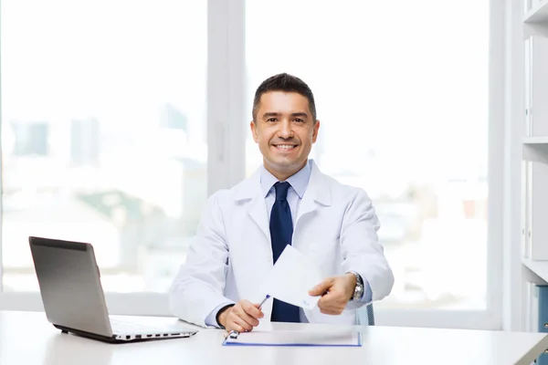 Happy doctor with prescription and laptop