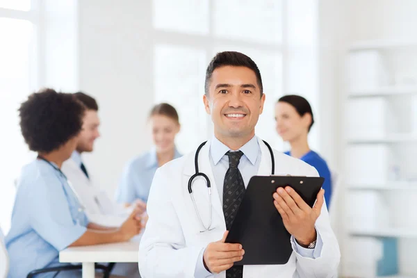 Happy doctor with clipboard over medical team