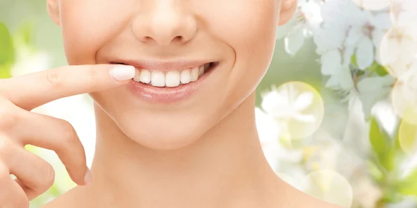 Close up of smiling woman face pointing to teeth