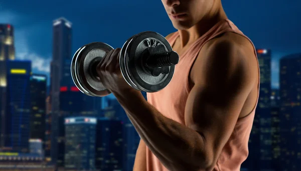 Close up of young man with dumbbell flexing biceps