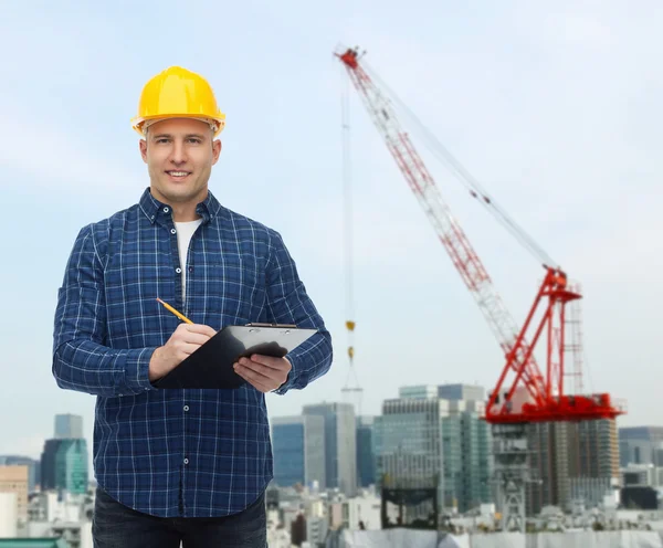 Smiling male builder in helmet with clipboard