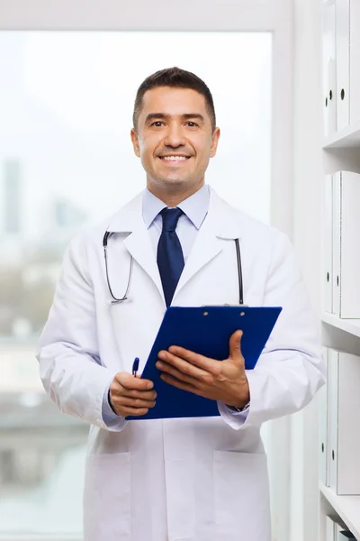 Happy doctor with clipboard in medical office