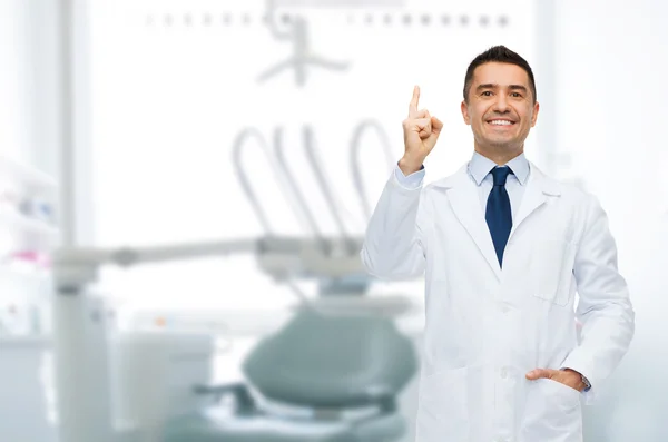 Smiling male dentist pointing finger up