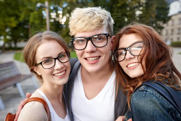 Happy teenage students in eyeglasses at campus