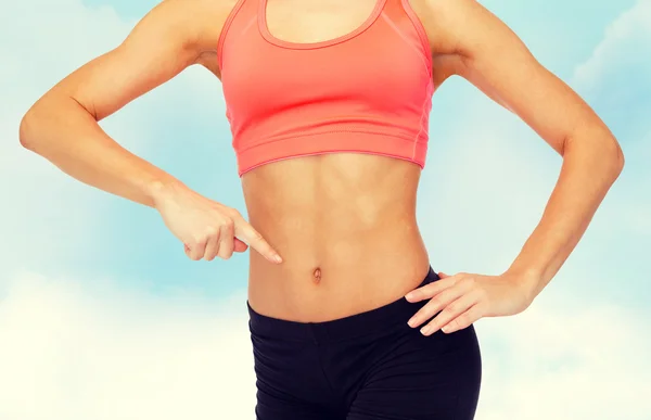 Close up of woman pointing finger at her six pack