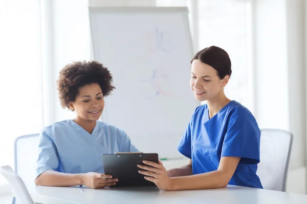 Happy doctors with tablet pc meeting at hospital