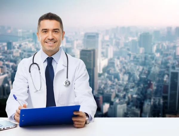 Happy doctor with clipboard over city background