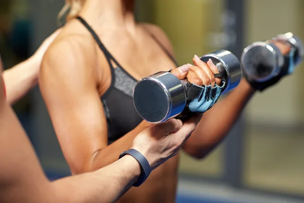 Woman with dumbbells flexing muscles in gym