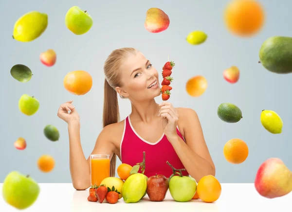 Woman with juice and fruits eating strawberries