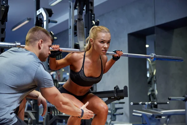 Man and woman with bar flexing muscles in gym