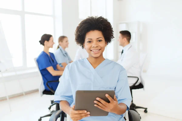 Happy nurse with tablet pc over team at hospital