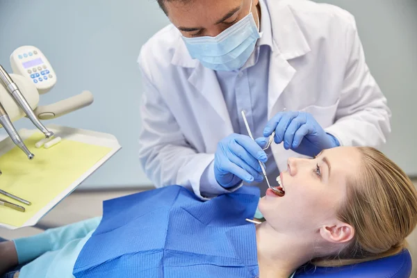 Male dentist in mask checking female patient teeth