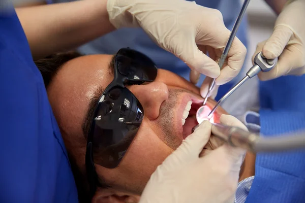 Dentist hands treating male patient teeth