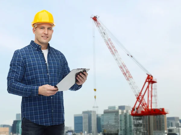 Smiling male builder in helmet with clipboard