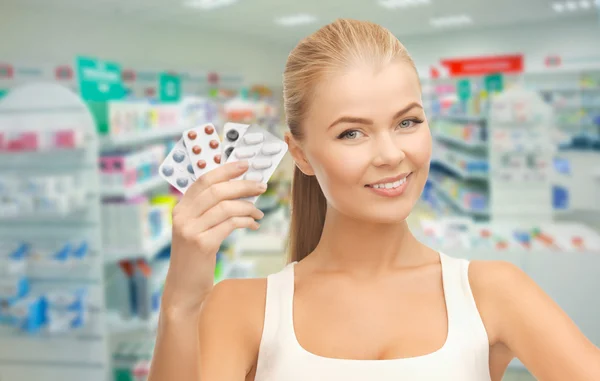 Young woman with pills in drugstore or pharmacy