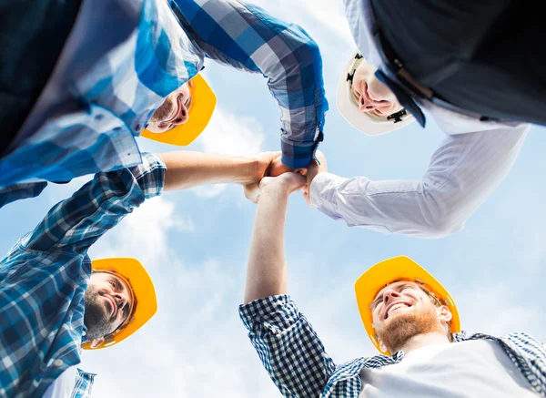 Close up of builders in hardhats making high five