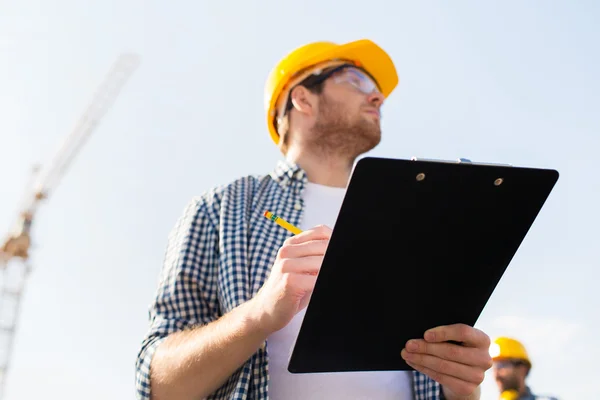 Builder in hardhat with clipboard outdoors