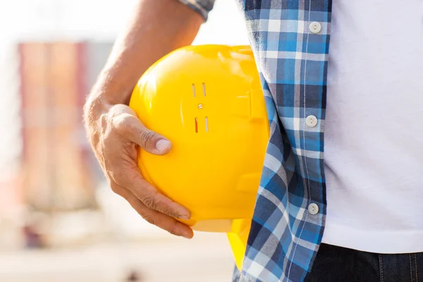 Close up of builder hand holding hardhat outdoors