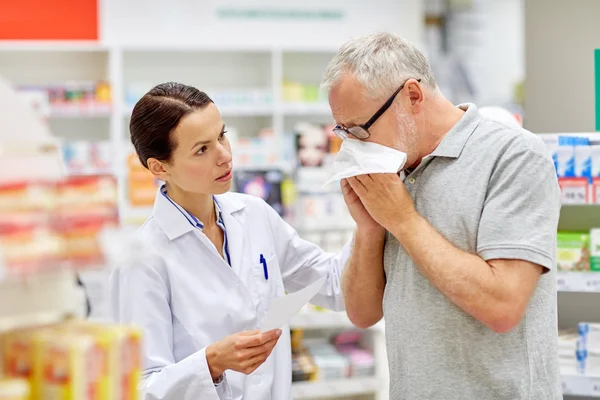 Pharmacist and senior man with flu at pharmacy