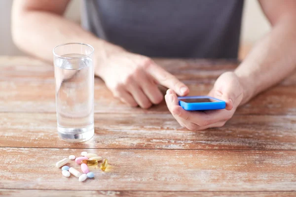 Close up of hands with smartphone, pills and water