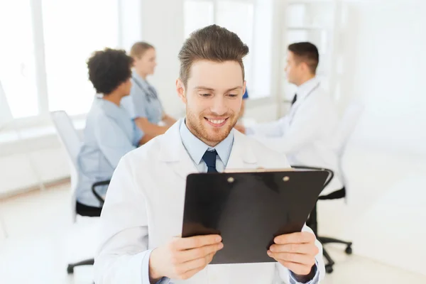 Happy doctor with tablet pc over team at clinic