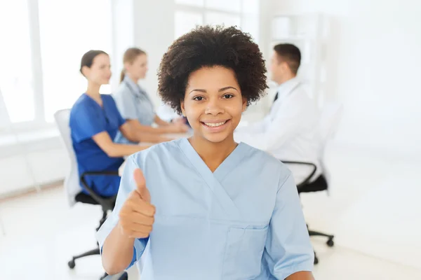 Happy female doctor or nurse showing thumbs up