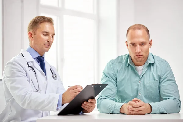 Male doctor and patient with clipboard at hospital