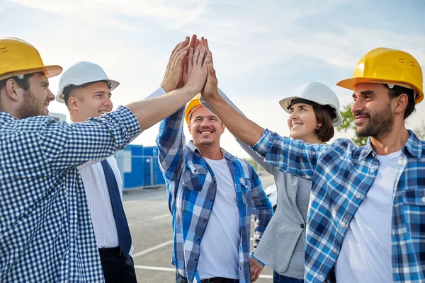 Close up of builders in hardhats making high five