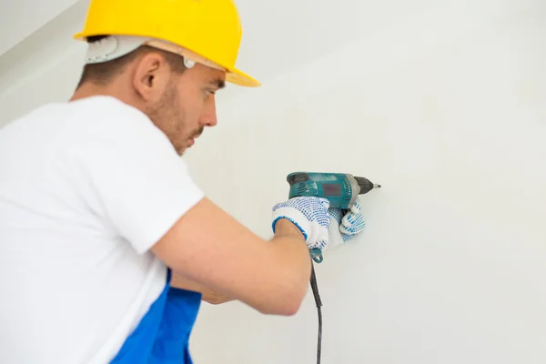 Close up of builders with drill perforating wall