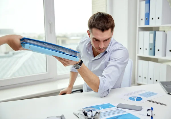 Businessman taking papers from secretary in office