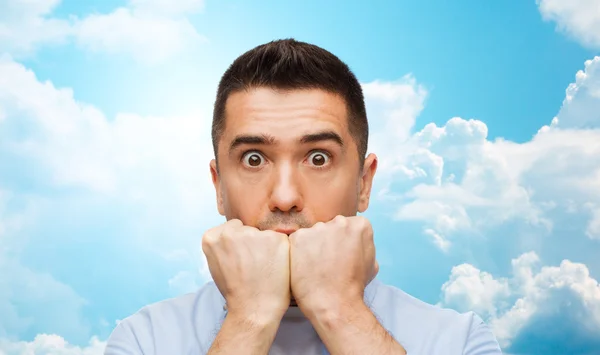 Scared man over blue sky and clouds background