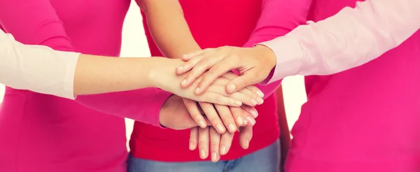 Close up of women in pink shirts with hands on top
