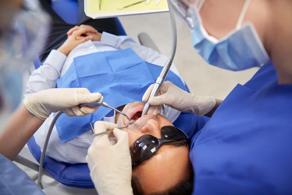 Dentist treating male patient teeth