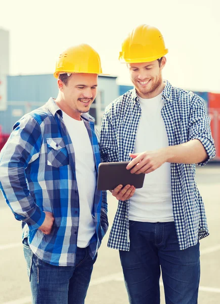 Smiling builders in hardhats with tablet pc