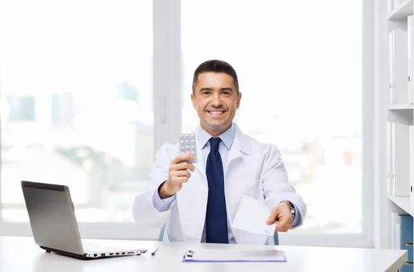 Smiling doctor with tablets and laptop in office
