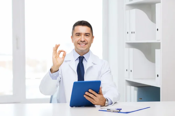 Smiling doctor with tablet pc showing ok hand sign