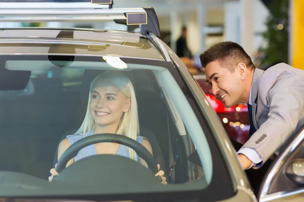 Happy woman with car dealer in auto show or salon