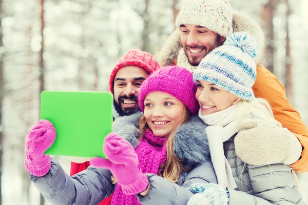 Smiling friends with tablet pc in winter forest