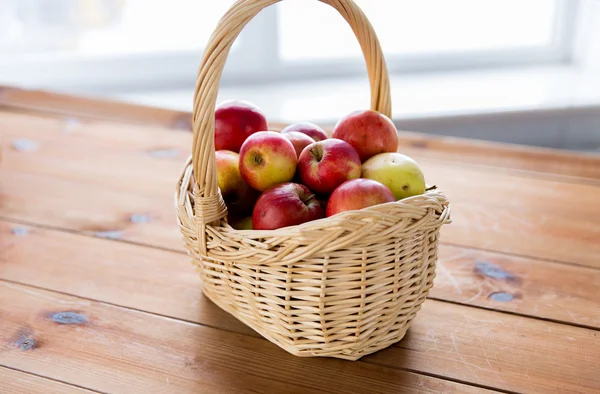 Close up of basket with apples on wooden table