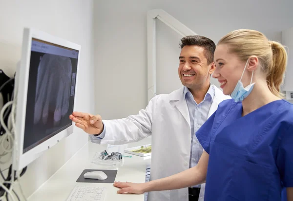 Dentists with x-ray on monitor at dental clinic