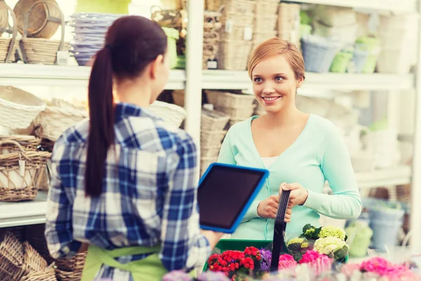 Happy women with tablet pc at flower shop