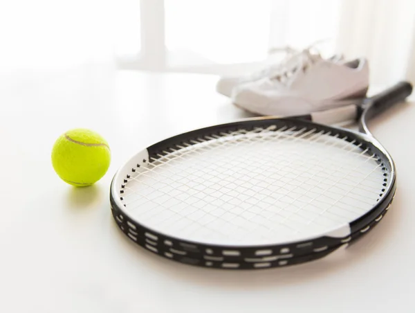 Close up of tennis racket with ball and sneakers
